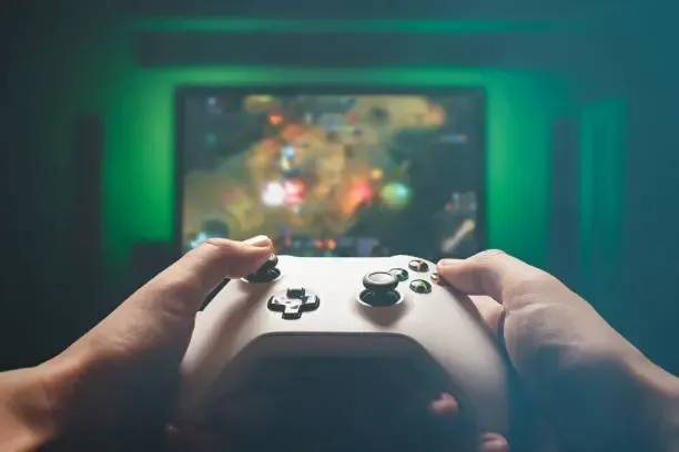 hands playing an xbox on a tv