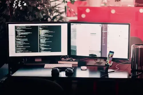 desktop set up for pc gaming with two screens on a dark table