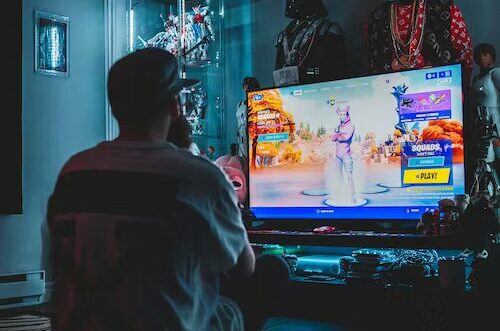 man playing game consoles on a tv in the dark